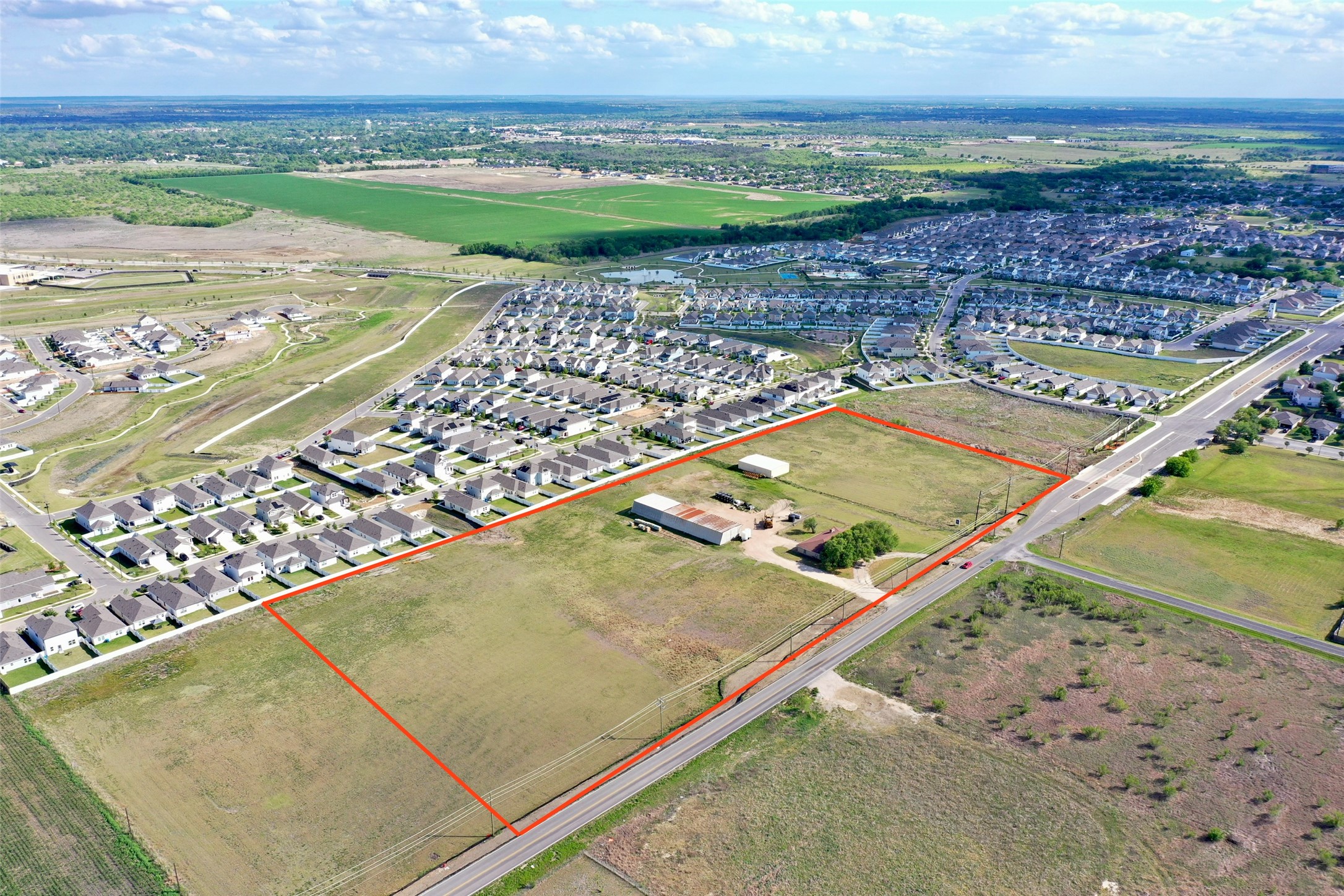 14601 County Line Road Elgin, TX 78621 - Photo 2 of 5 This aerial view showcases a expansive land parcel, outlined in red, featuring a building structure and open fields