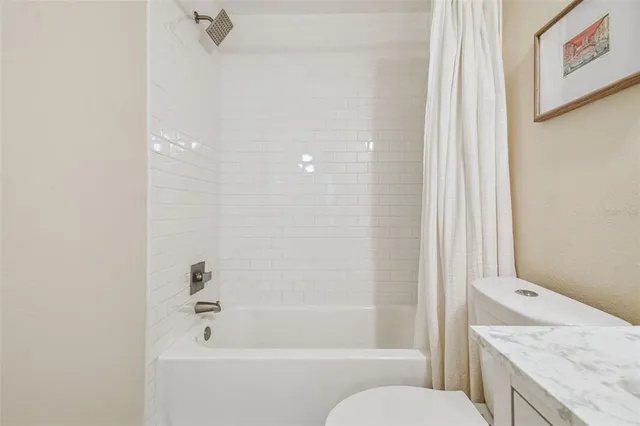 a bathroom with a granite countertop sink a toilet and shower