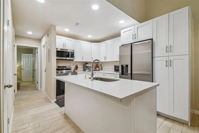 a kitchen with kitchen island a refrigerator sink and cabinets