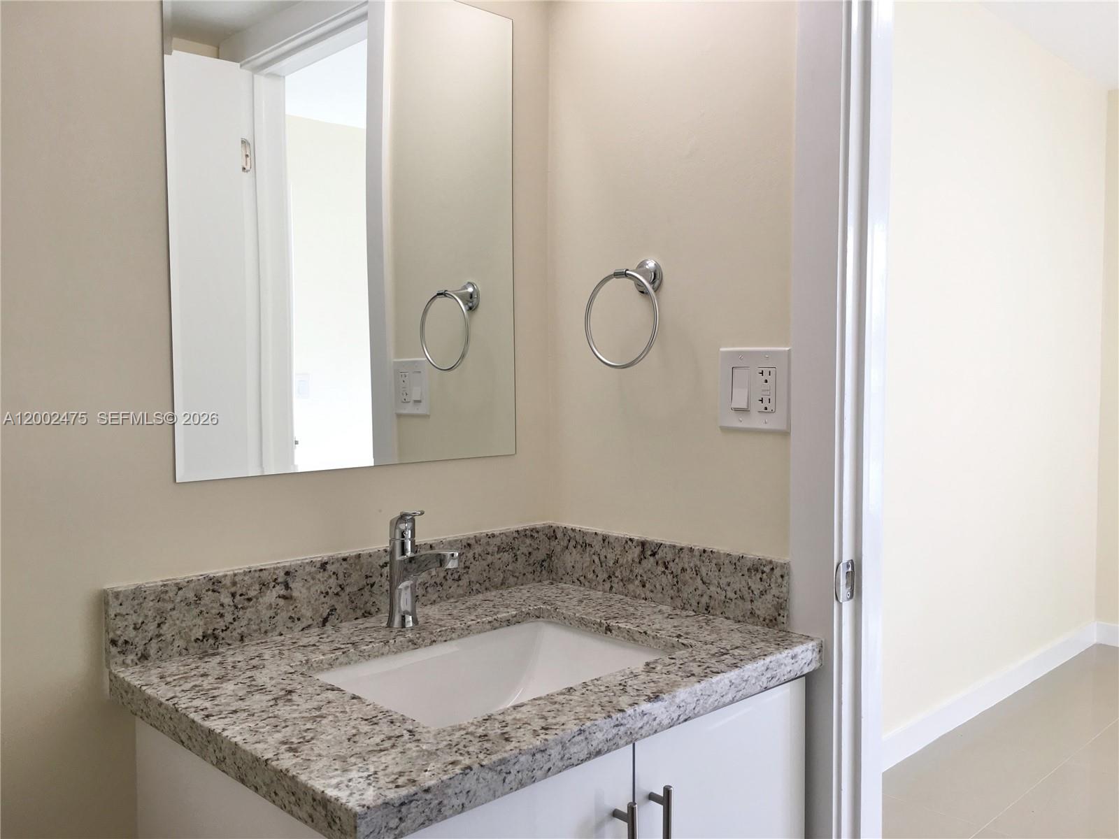 4709 Northwest 7th Street, Unit 1079 Miami, FL 33126 - Photo 14 of 28 a bathroom with a granite countertop sink and a mirror