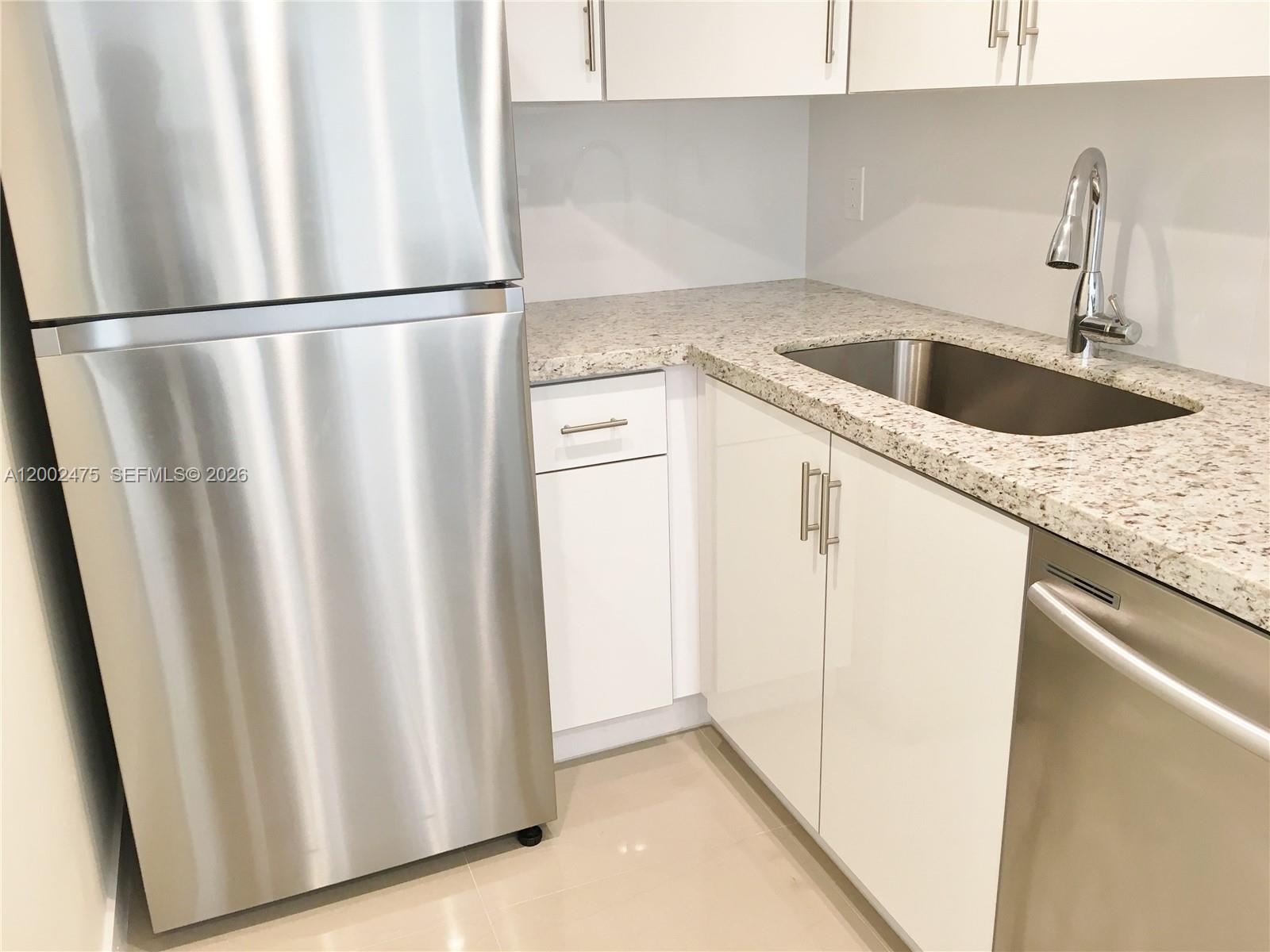 4709 Northwest 7th Street, Unit 1079 Miami, FL 33126 - Photo 4 of 28 a kitchen with refrigerator a sink and cabinets