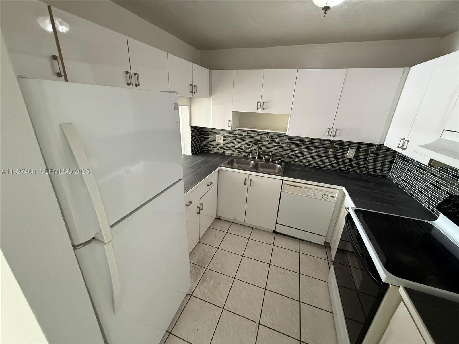 1900 West 68th Street, Unit G308 Hialeah, FL 33014 - Photo 3 of 10 a kitchen with white cabinets stove and sink