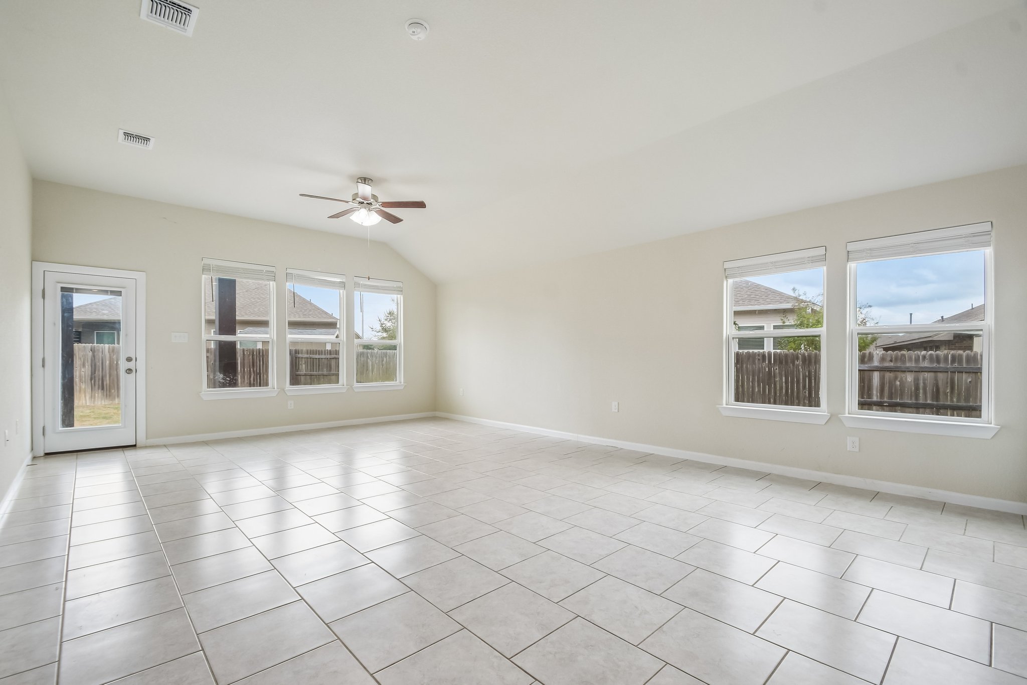 Ample windows invite natural light across the polished tile floors in this spacious living area.