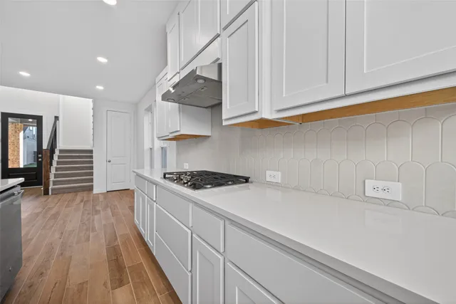a kitchen with granite countertop a stove and a wooden floors