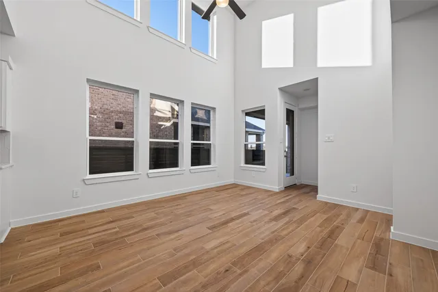 a view of an empty room with wooden floor and windows