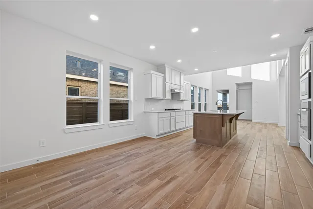a large white kitchen with wooden floors and view living room