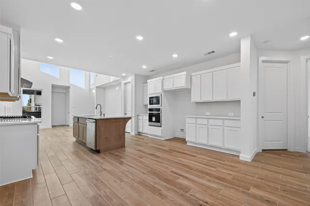 a kitchen with stainless steel appliances kitchen island wooden floors and white cabinets