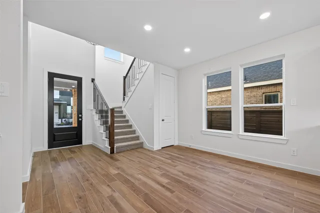a view of an empty room with wooden floor and windows