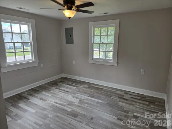 a view of empty room with wooden floor and fan
