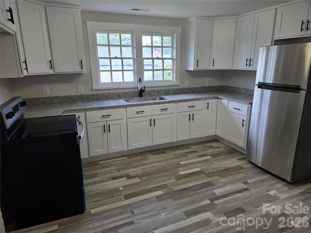 a kitchen with granite countertop white cabinets and refrigerator