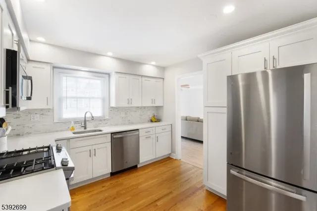 a kitchen with a refrigerator a sink and wooden floor
