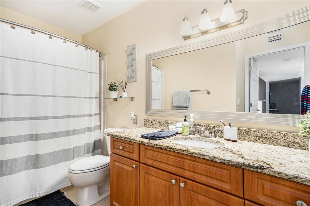 455 Alt 19, Unit 65 Palm Harbor, FL 34683 - Photo 12 of 16 a bathroom with a granite countertop sink a toilet and a mirror