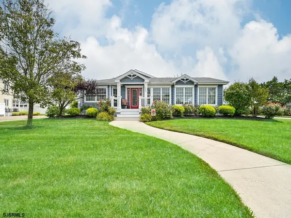 a front view of a house with a garden and trees