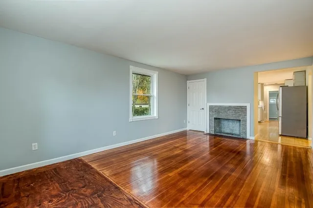 wooden floor fireplace and windows in an empty room