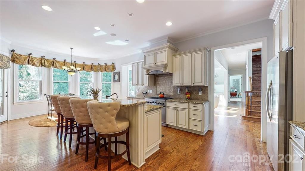 8116 Balcony Bridge Road Huntersville, NC 28078 - Photo 12 of 31 a kitchen with stainless steel appliances granite countertop a stove top oven a sink dishwasher a dining table and chairs with wooden floor