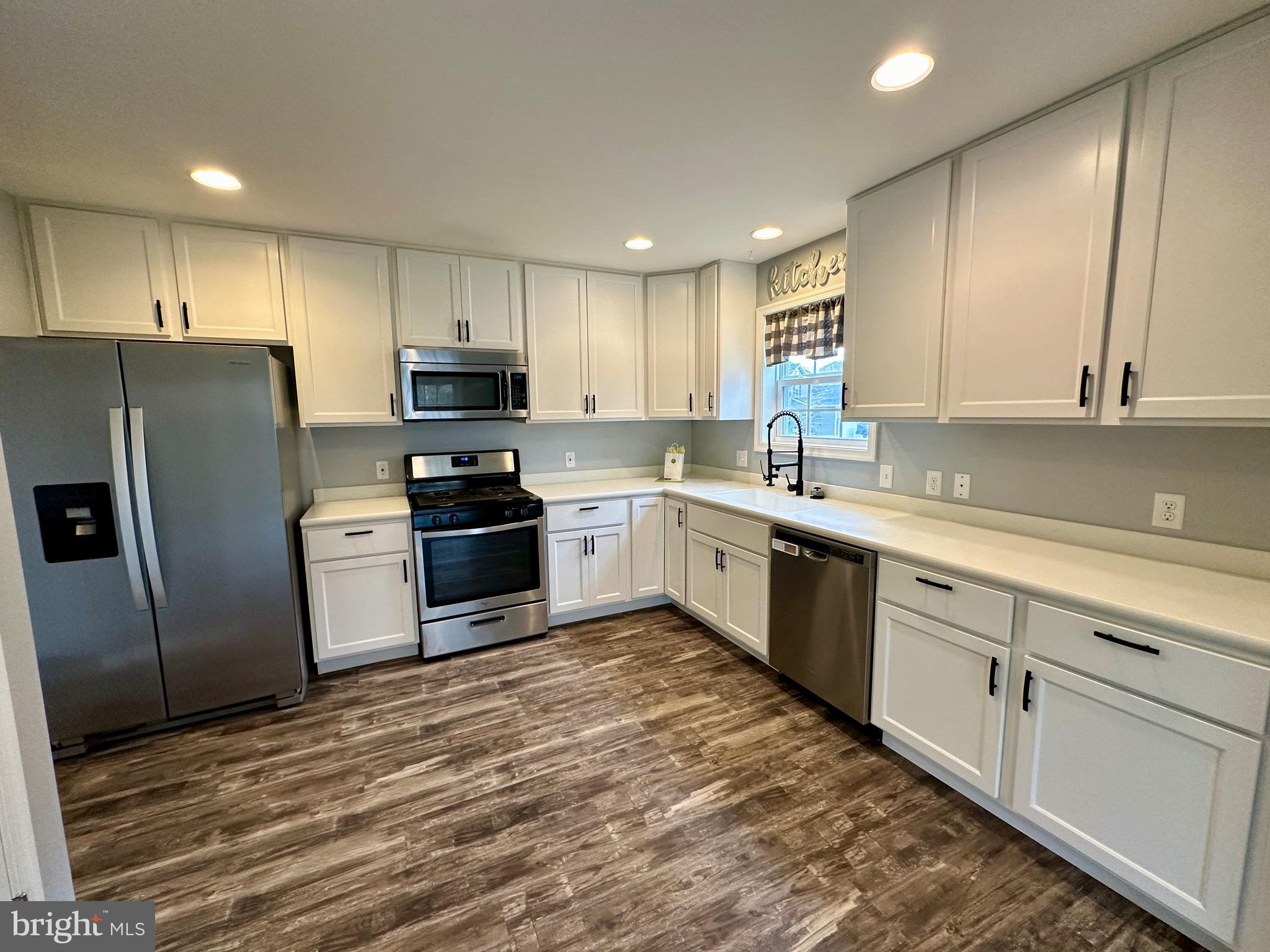 326 Sweeping Mist Circle Frederica, DE 19946 - Photo 15 of 37 a kitchen with granite countertop a refrigerator sink and white cabinets