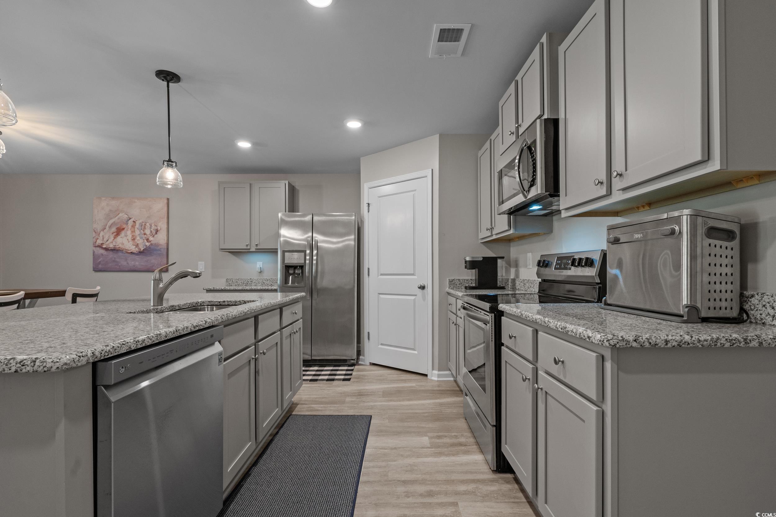 1803 Promise Pl. Myrtle Beach, SC 29588 - Photo 11 of 40 Kitchen with appliances with stainless steel finishes, gray cabinets, decorative light fixtures, a kitchen island with sink, and light stone counters