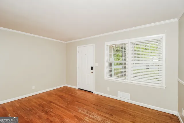 a view of an empty room with wooden floor and a window