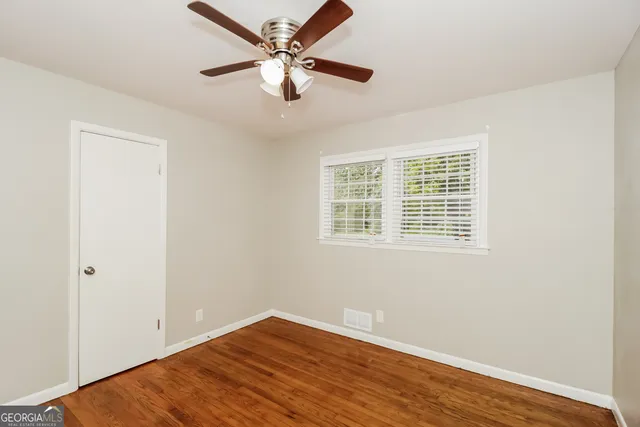 an empty room with wooden floor fan and windows