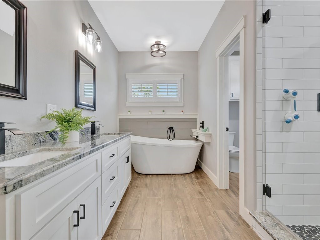 1105 C C Road Diboll, TX 75941 - Photo 26 of 40 a spacious bathroom with a granite countertop tub sink a mirror a shower and vanity