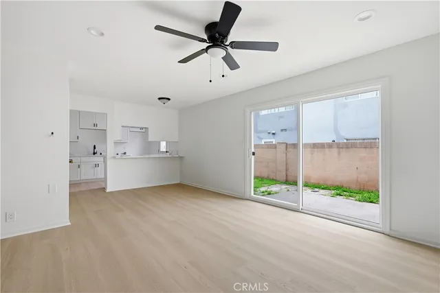 a view of an empty room with a window and a kitchen view
