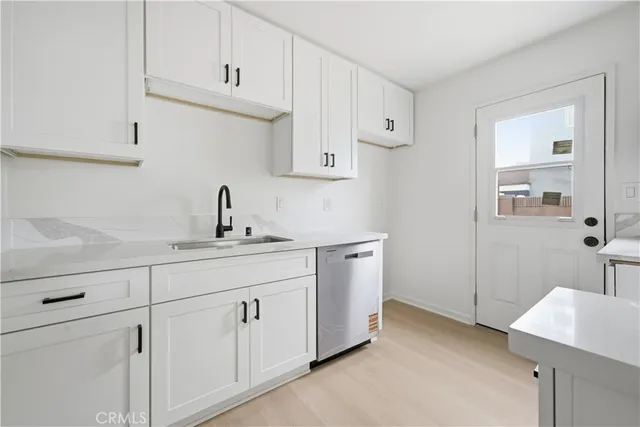 a kitchen with white cabinets and sink