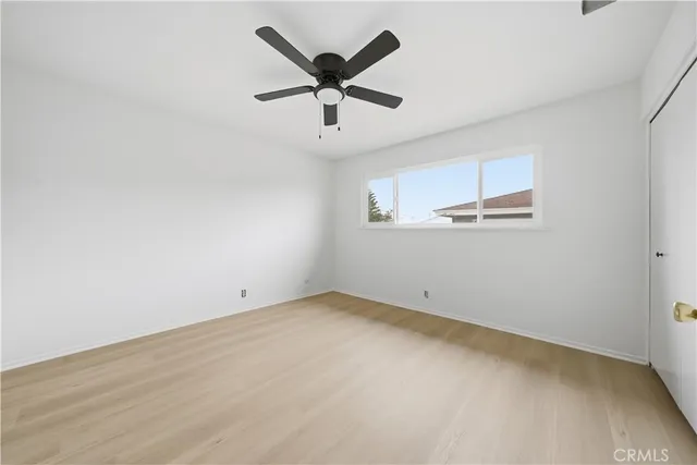 an empty room with ceiling fan and window