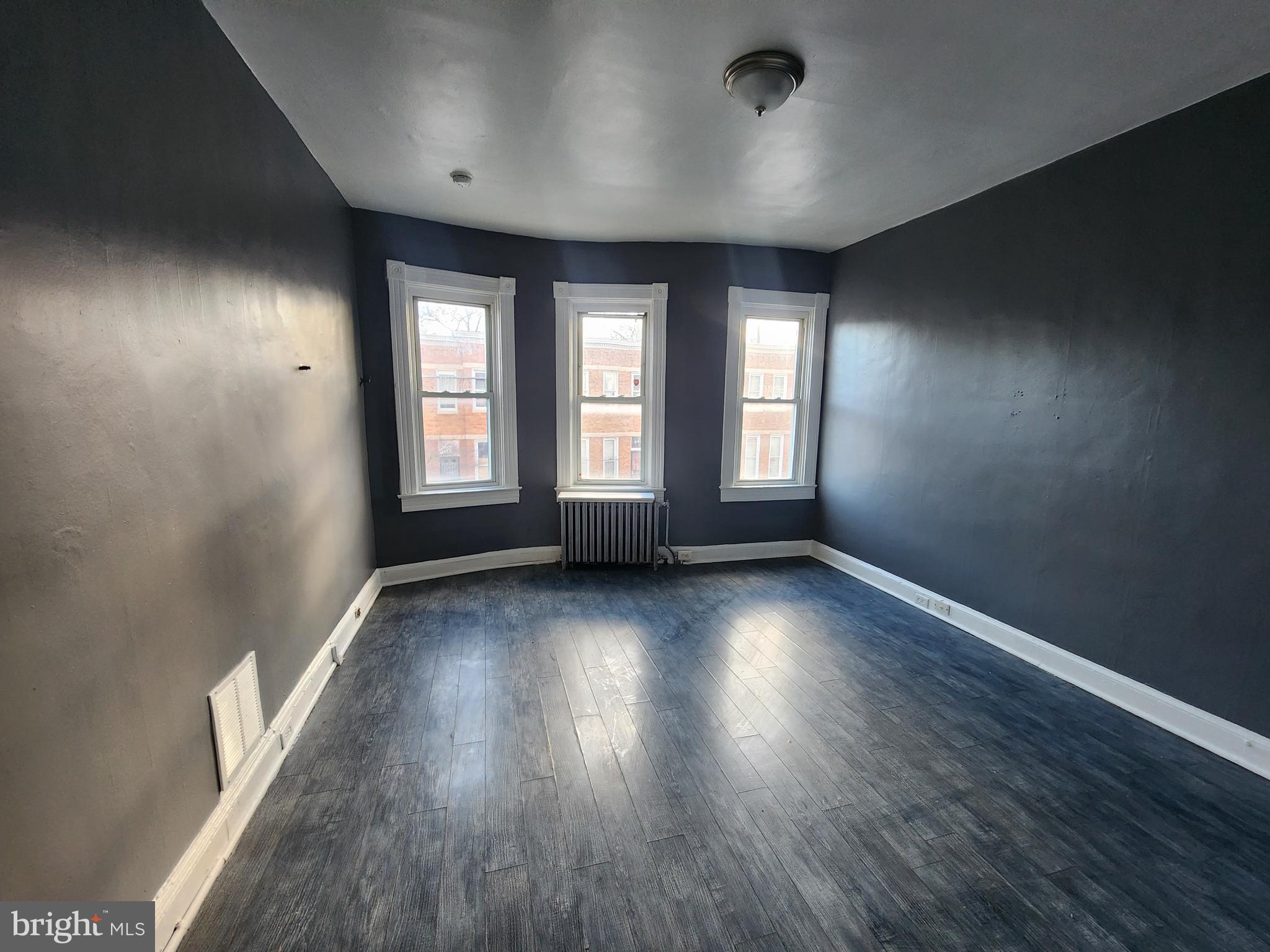810 Appleton Street Baltimore, MD 21217 - Photo 26 of 27 an empty room with wooden floor and windows