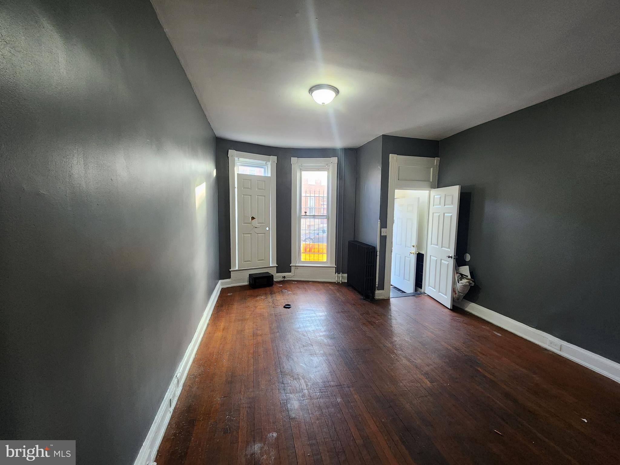 810 Appleton Street Baltimore, MD 21217 - Photo 5 of 27 an empty room with wooden floor and windows