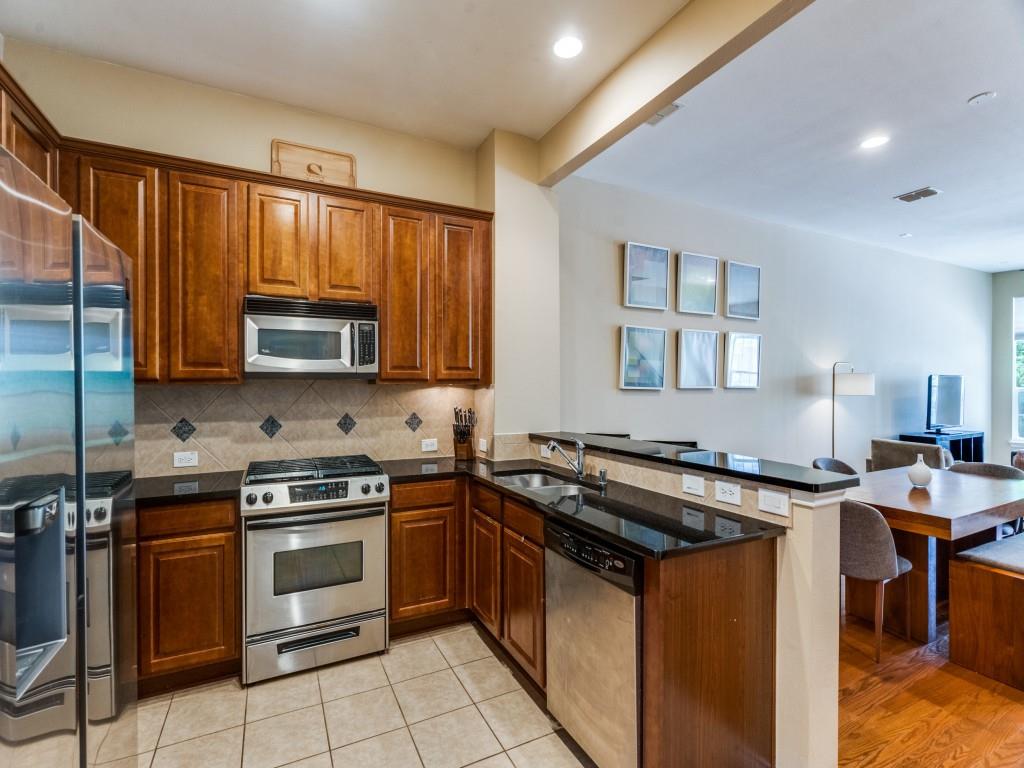 15711 Spectrum Drive, Unit 80 Addison, TX 75001 - Photo 13 of 26 a kitchen with granite countertop a stove top oven microwave and cabinets