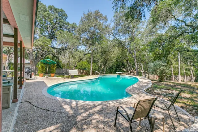 a view of backyard with swimming pool and seating space