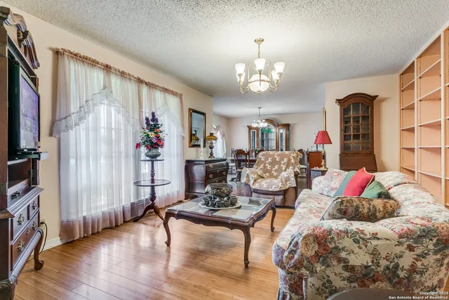 a living room with furniture chandelier and wooden floor
