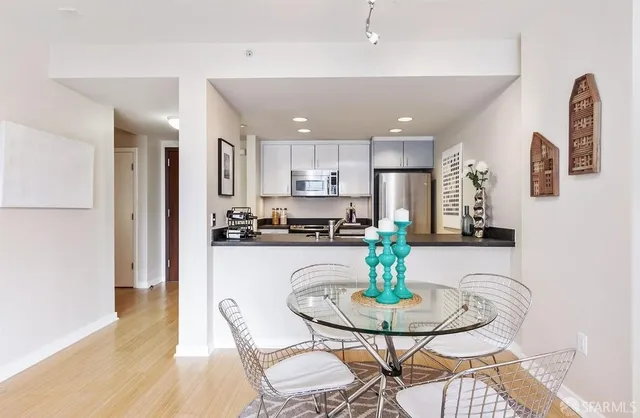 a kitchen with stainless steel appliances granite countertop a refrigerator a stove a sink dishwasher and white dining table with wooden floor