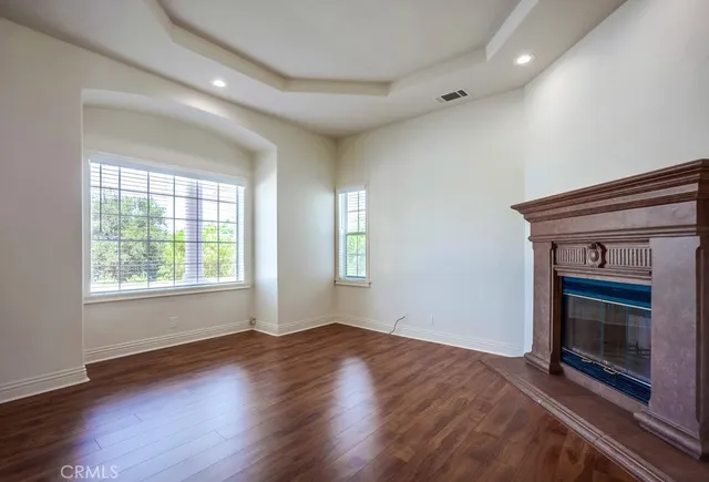 an empty room with wooden floor fireplace and windows