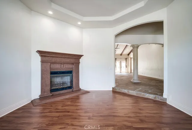 a view of an empty room with wooden floor and a fireplace