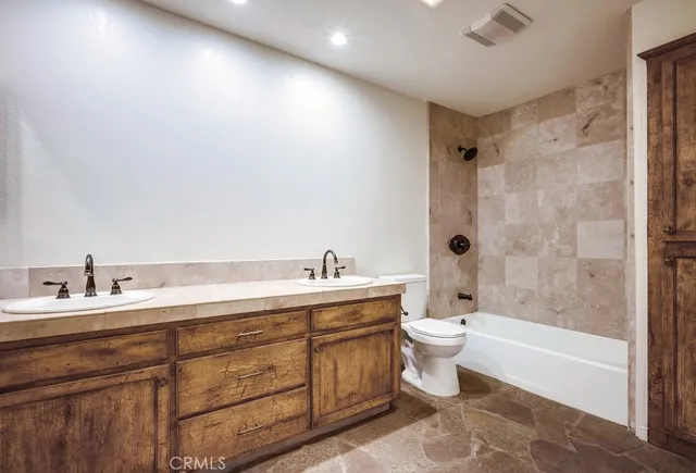 a bathroom with a double vanity sink toilet mirror and bathtub