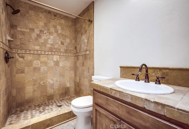 a bathroom with a granite countertop sink toilet and shower