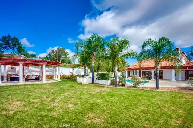 a view of a house with a big yard and palm trees