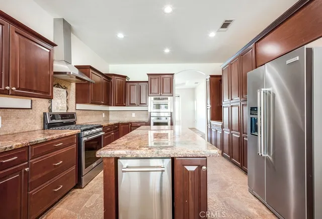 a kitchen with stainless steel appliances granite countertop a refrigerator a sink and a stove