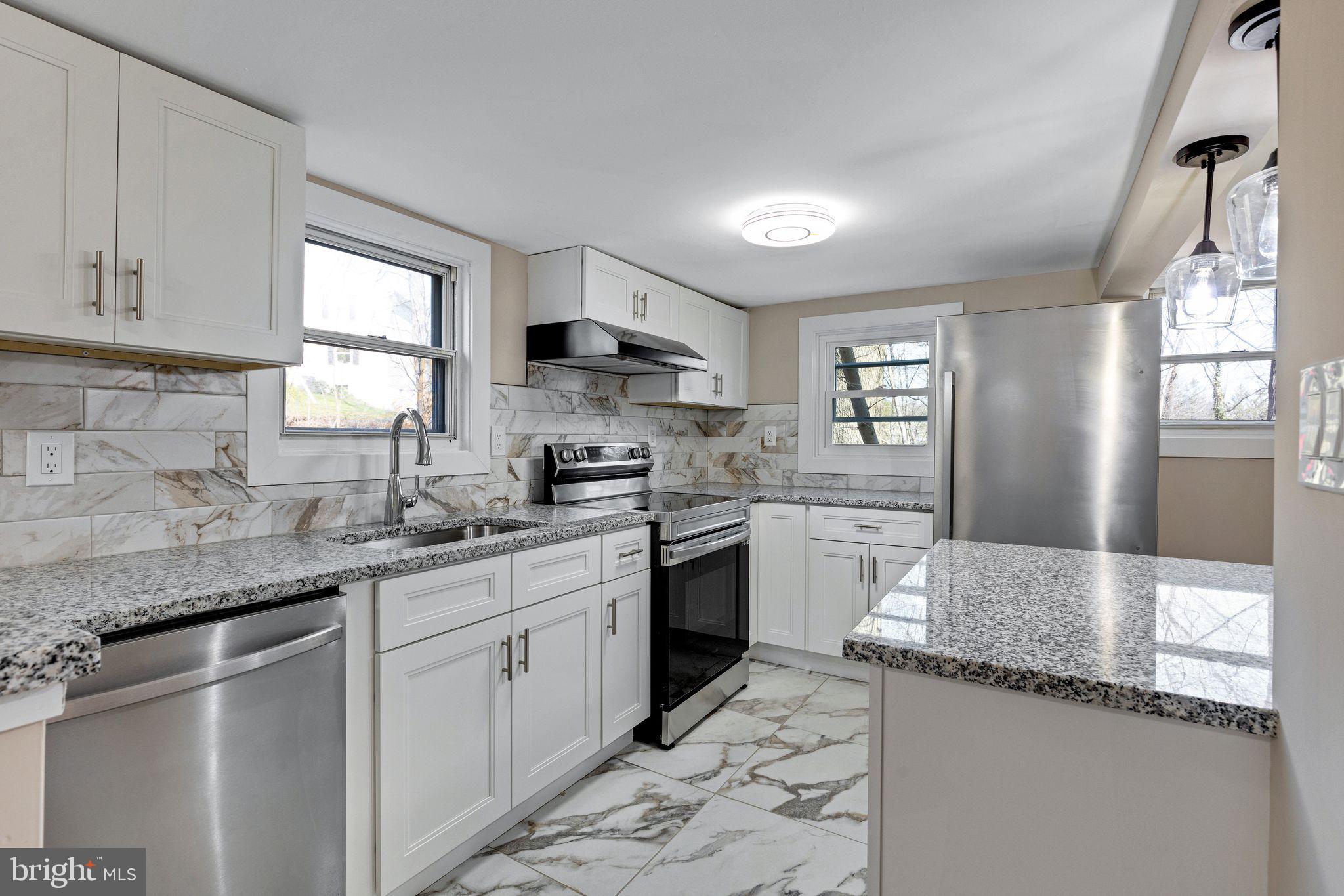 a kitchen with granite countertop a sink a counter top space cabinets and stainless steel appliances