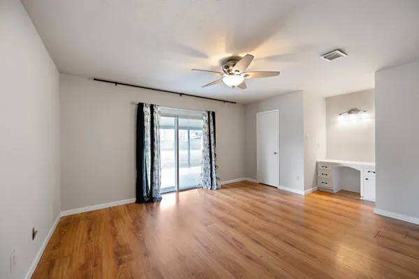 a view of empty room with wooden floor and fan