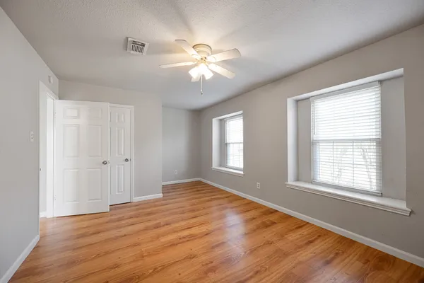 a view of an empty room with wooden floor and a window