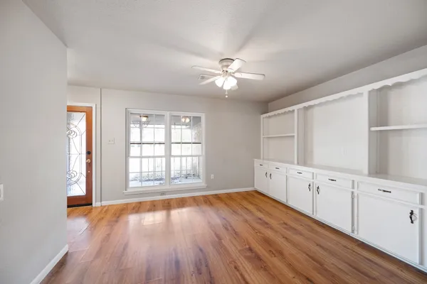 a view of an empty room with a window and wooden floor