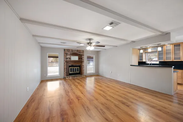 a view of a big room with wooden floor and a kitchen