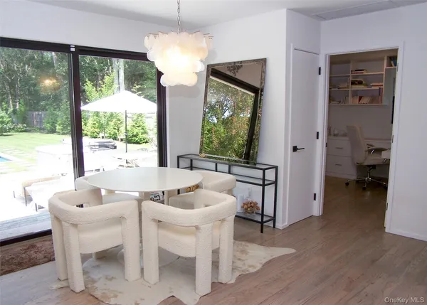 a dining room with wooden floor a chandelier a glass table and chairs