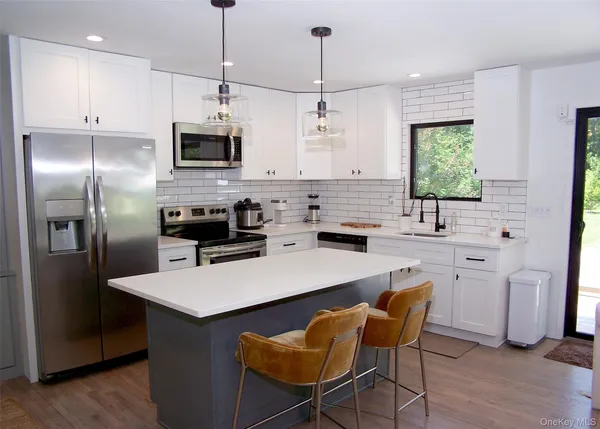 a kitchen with stainless steel appliances a stove a sink a refrigerator a kitchen island a stove a table and chairs