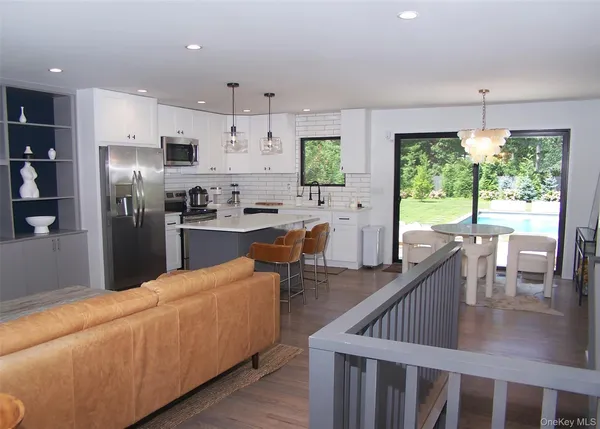 a kitchen with stainless steel appliances kitchen island granite countertop a refrigerator a sink a stove and a dining table with wooden floor