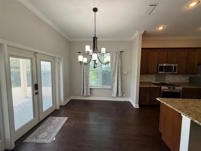 a open kitchen with stainless steel appliances granite countertop a refrigerator a sink dishwasher a stove and a dining table with wooden floor