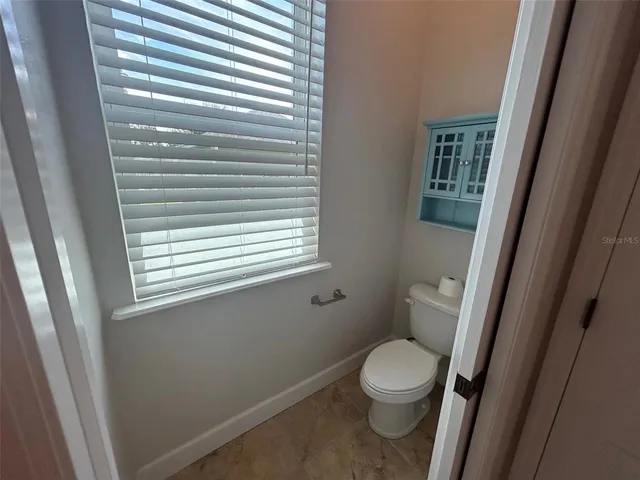 a white toilet sitting in a bathroom next to a window