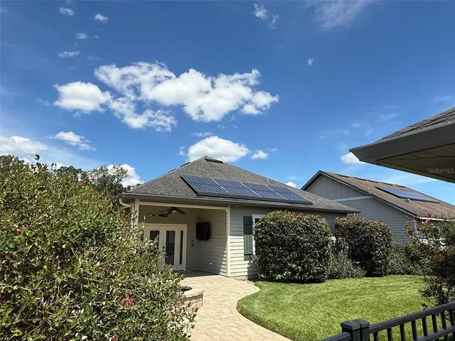 a view of a house with small yard plants and large tree